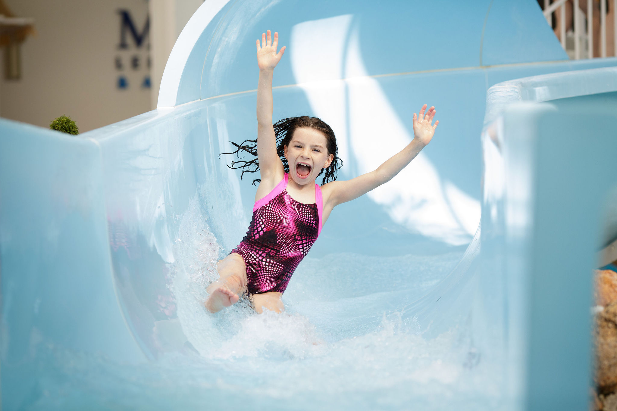 Young girl rides the flumes with her hands in the air